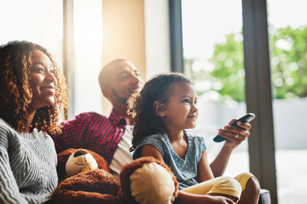 Shot of a happy young family of three watching tv from the sofa at home