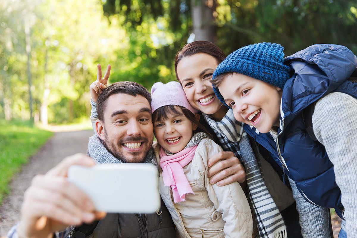 family with backpacks taking selfie by smartphone